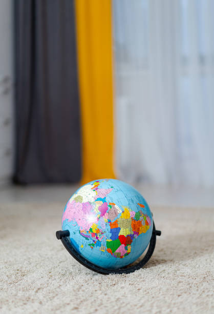 istock A colorful globe on a plush carpet with curtains in the background. A vibrant globe rests on a soft 2186751584