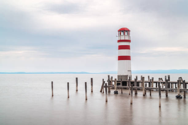 Podersdorf Am See, Austria - April 7, 2023: Lighthouse with wooden pier at lake.