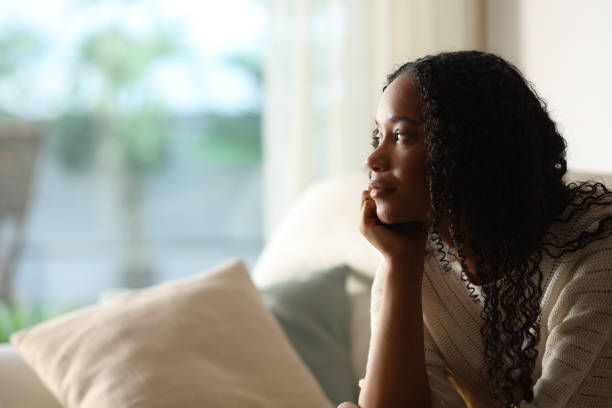 istock Black woman contemplating through a window at home 2186755837
