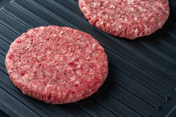 istock Raw hamburger patty on grill 2186759334