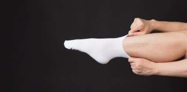 istock Asian Male legs wear white sock and hand is pulling a sock on black background. 2186759530