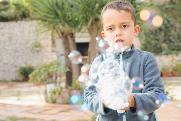 istock Preschool child having fun making soap bubbles with a recycled plastic bottle in a garden 2186763535