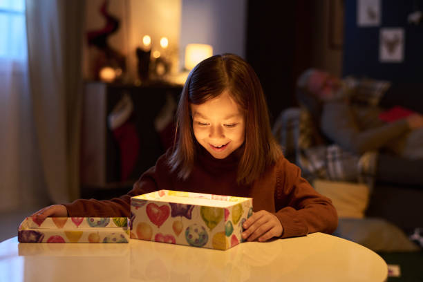 istock Smiling Girl Holding Illuminated Gift Box Indoor 2186765682