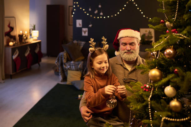 istock Decorating Christmas Tree with Grandfather Wearing Santa Hat 2186765699
