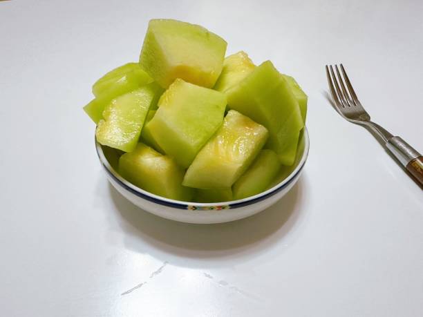 Fresh melon cubes neatly arranged in a bowl, showcasing their vibrant orange and green hues. A refreshing and visually appealing treat, perfect for any occasion.