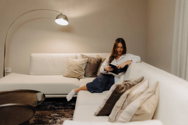 istock Woman reading book at home at night 2186770362