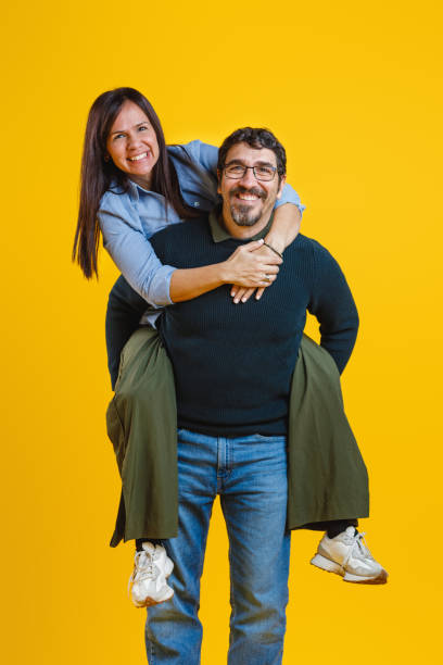 istock Joyful Couple in Fun Piggyback Pose on Yellow Background 2186772004