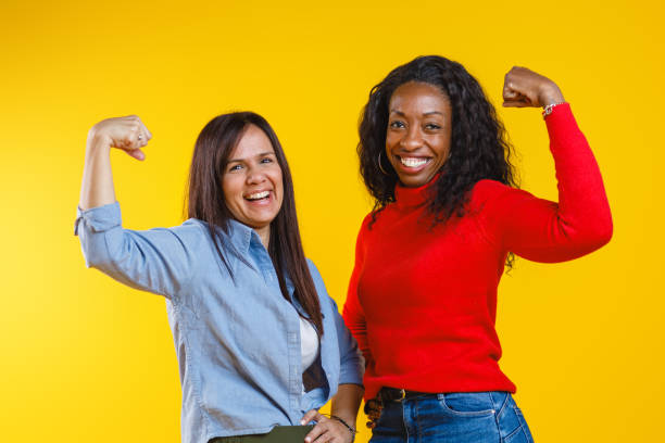 istock Two Women Celebrating Strength and Positivity on Yellow Background 2186772011