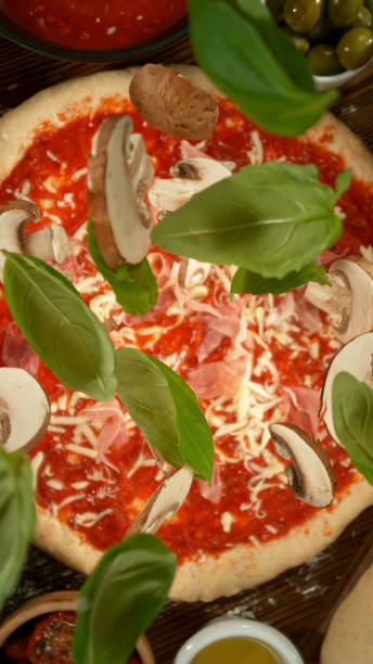 Pizza on a rustic baking paper, served on a kitchen or restaurant table, with fresh vegetables, herbs and spices, representing a wellbeing and indulgence in food, city life and modern culture lifestyle, street food culture