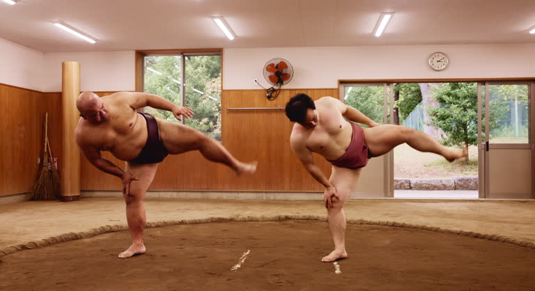 Stretching, sumo and tournament with Japanese people in arena for training, shiko ritual and wrestling. Festival, competition and game with asian men in dohyo ring of temple for culture and sports