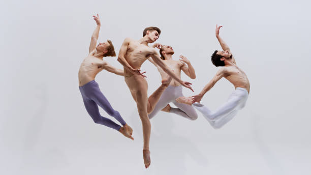istock Four dancers leap in unison, their bodies creating powerful visual of strength and grace through rigorous training against white studio background. 2186772798