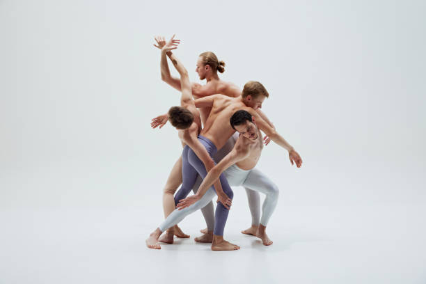 istock Group of dancers entwine their bodies in complex pose, capturing beauty of synchronized movement against white studio background. 2186772819