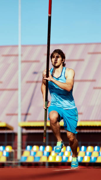 istock Motivated young man, pole jumping athlete in motion, practicing pole vaulting, aiming to reach new heights. Outdoor stadium 2186776044