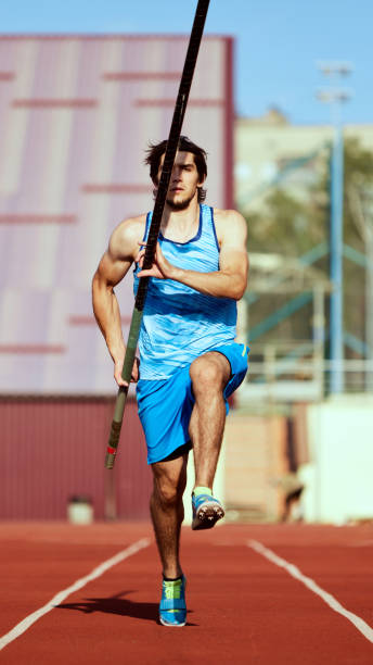 istock Pole jump athlete, young focused man in blue uniform on stadium track, running with pole, getting ready for high jump 2186776046
