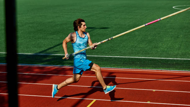 istock High jump practice session, with focused and strong young man, pole vaulter in blue uniform in motion, running with pole at outdoor stadium 2186776057