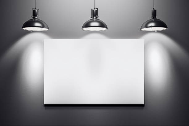 istock Blank white canvas on a dark wall with three metal lamps casting spotlights. 3D Rendering 2186777021