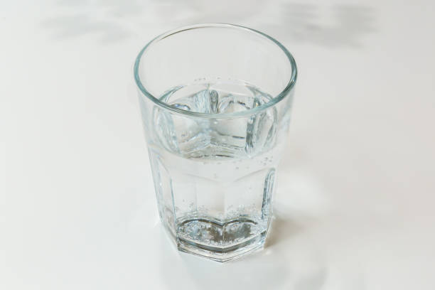 istock Faceted glass with drink water on a white table 2186778985