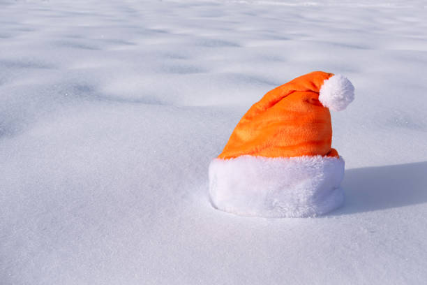 An orange Santa hat resting on a snowy surface. This warm and vibrant image creates a cozy holiday vibe, ideal for greeting card backgrounds or festive projects.