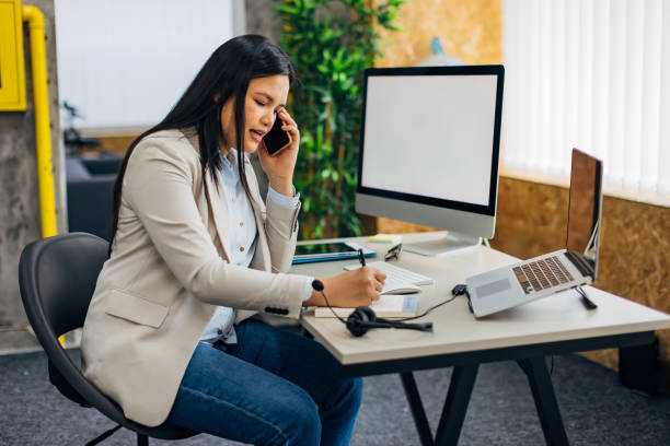 istock Filipino customer service representative makes a business call while sitting in a desk chair in the office 2186780019