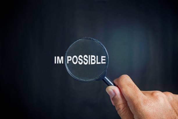 istock Hand holding a magnifying glass focuses on possible from the word impossible on a dark background. Motivational or inspirational concept. 2186780040