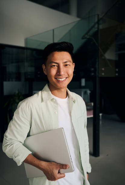 istock Young asian freelancer smiling and holding laptop in modern office 2186780878