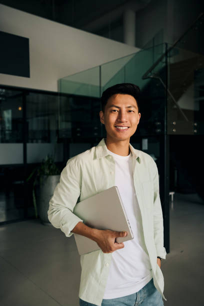 istock Young asian freelancer smiling and holding laptop in modern office 2186780881