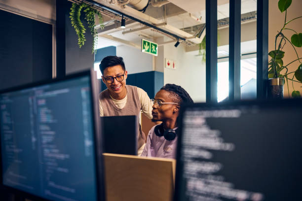 software developers working together on code in modern office - programador imagens e fotografias de stock