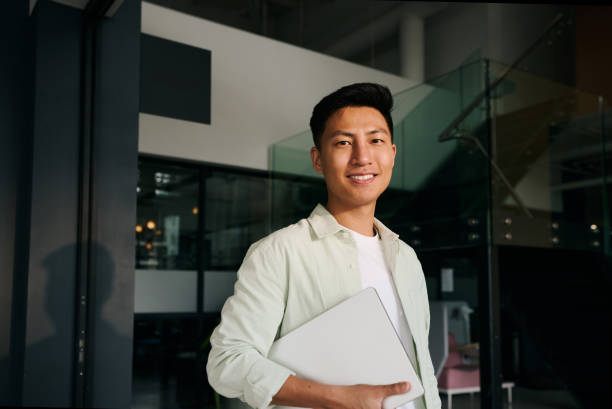 istock Young asian freelancer smiling and holding laptop in modern office 2186780967