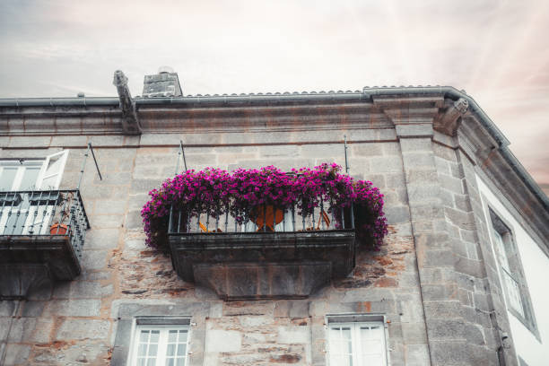 A balcony with a pink flower arrangement and a number 45 on it. The flowers are in a hanging basket and the balcony is attached to a building