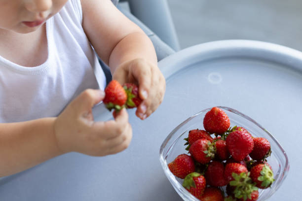 istock Little child taking strawberry from the plate. 2186790053
