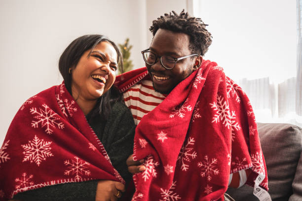 Joyful couple laughing while wrapped in festive red blanket