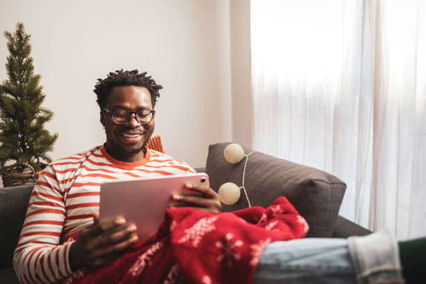 istock Man relaxing on sofa with tablet during holiday season 2186797117