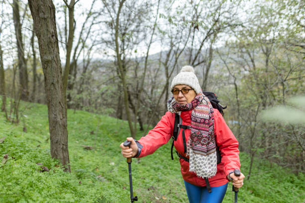 istock Woman climbs through forest using hiking poles 2186798249