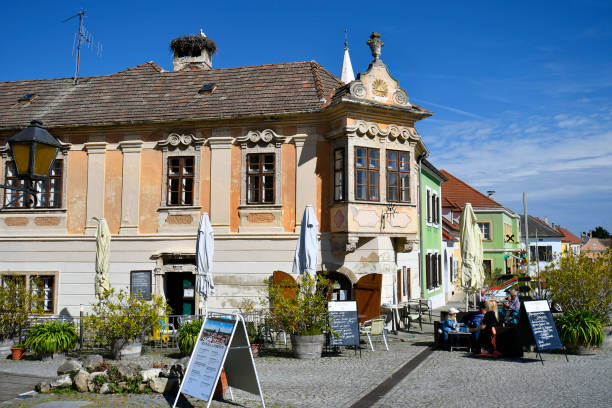 Rust, Austria - March 23, 2024: Unknown people relax on a warm spring day in a restaurant decorated with reliefs at the Town Hall Square in the so-called stork town on Lake Neusiedl with its picturesque houses, UNESCO World Heritage Site in Burgenland