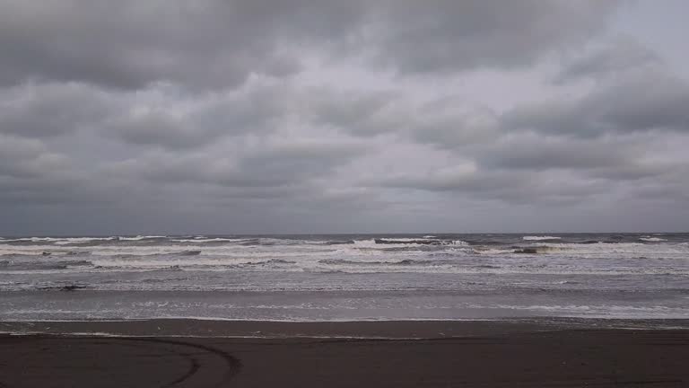 Lonely beach with cloudy sky and wind, wet sand, small waves, East Coast, Buenos Aires, Argentina.