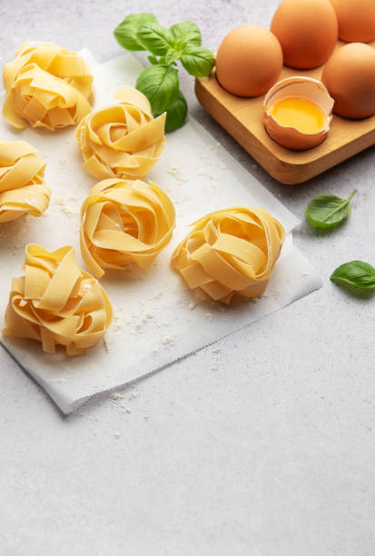 istock Fresh tagliatelle pasta nests with eggs and basil leaves on baking paper 2186803658