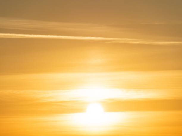 A golden sunrise with soft clouds creating a warm, serene atmosphere in the sky.
