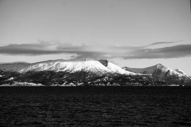 istock Monochrome snow-capped mountains with a calm sea. 2186813025