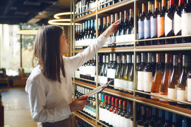 istock Professional woman sommelier getting wine bottle from shelves, making notes on tablet being at wine cellar. 2186815216