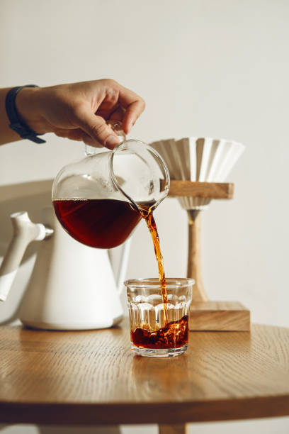 istock Pouring Fresh Black Coffee Into Glass from Pot on Sunlit Table 2186816722
