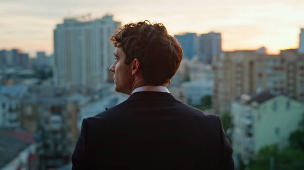 istock Back view businessman standing balcony overlooking city dusk. Confident man 2186816765