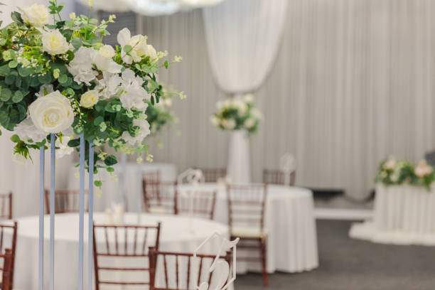 istock Decorated interior for festive event. Fancy table set for dinner with white flower composition in restaurant, luxury interior background. Wedding elegant banquet decoration arranged by catering service. 2186821381