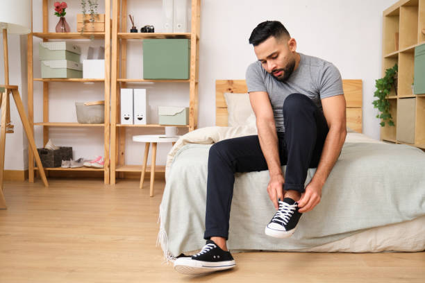 istock Young man tying shoelaces on bed in cozy bedroom 2186822455