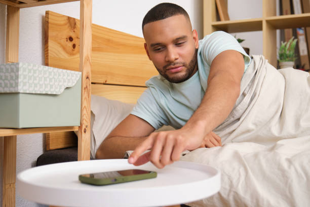 istock Young man turning off alarm on smartphone in bed 2186824204