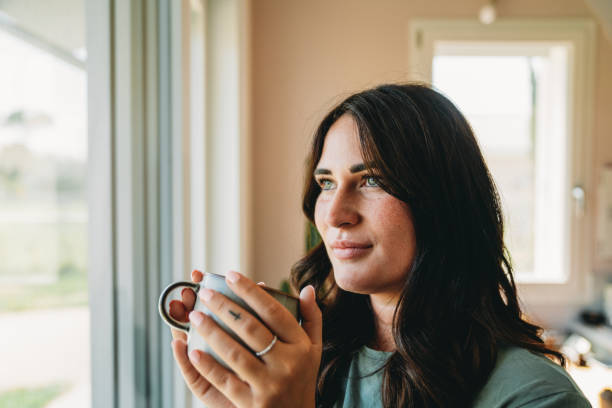 istock A young woman is drinking tea while she's looking through window 2186824697