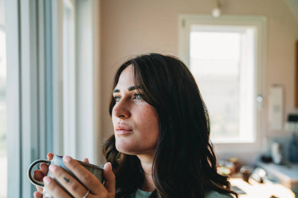 istock A young woman is drinking tea while she's looking through window 2186824702