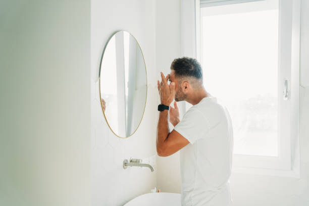 istock A millennial man is using a face cream in the bathroom 2186824833