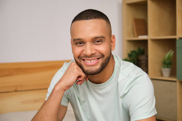istock Young man smiling and resting chin on hand in bedroom 2186825172