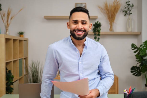 istock Smiling young middle eastern man holding documents in home office: 2186827147