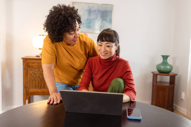 istock Two women happily browsing laptop together at home 2186836649